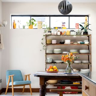 Freestanding shelves in a kitchen-diner next to a blue chair