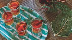 Glasses of hot toddy on a green and white plate with festive foliage