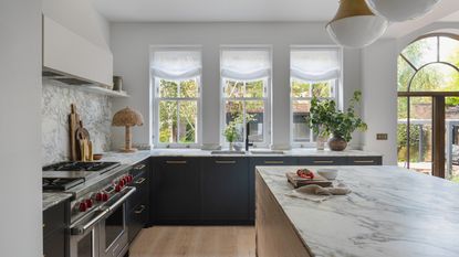 A modern kitchen with blue cabinets and a wooden island, with arched details throughout
