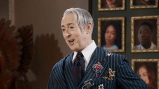 Alan Cumming wearing a blazer and broaches talking to the Traitors: New Blood cast after the first murder. 