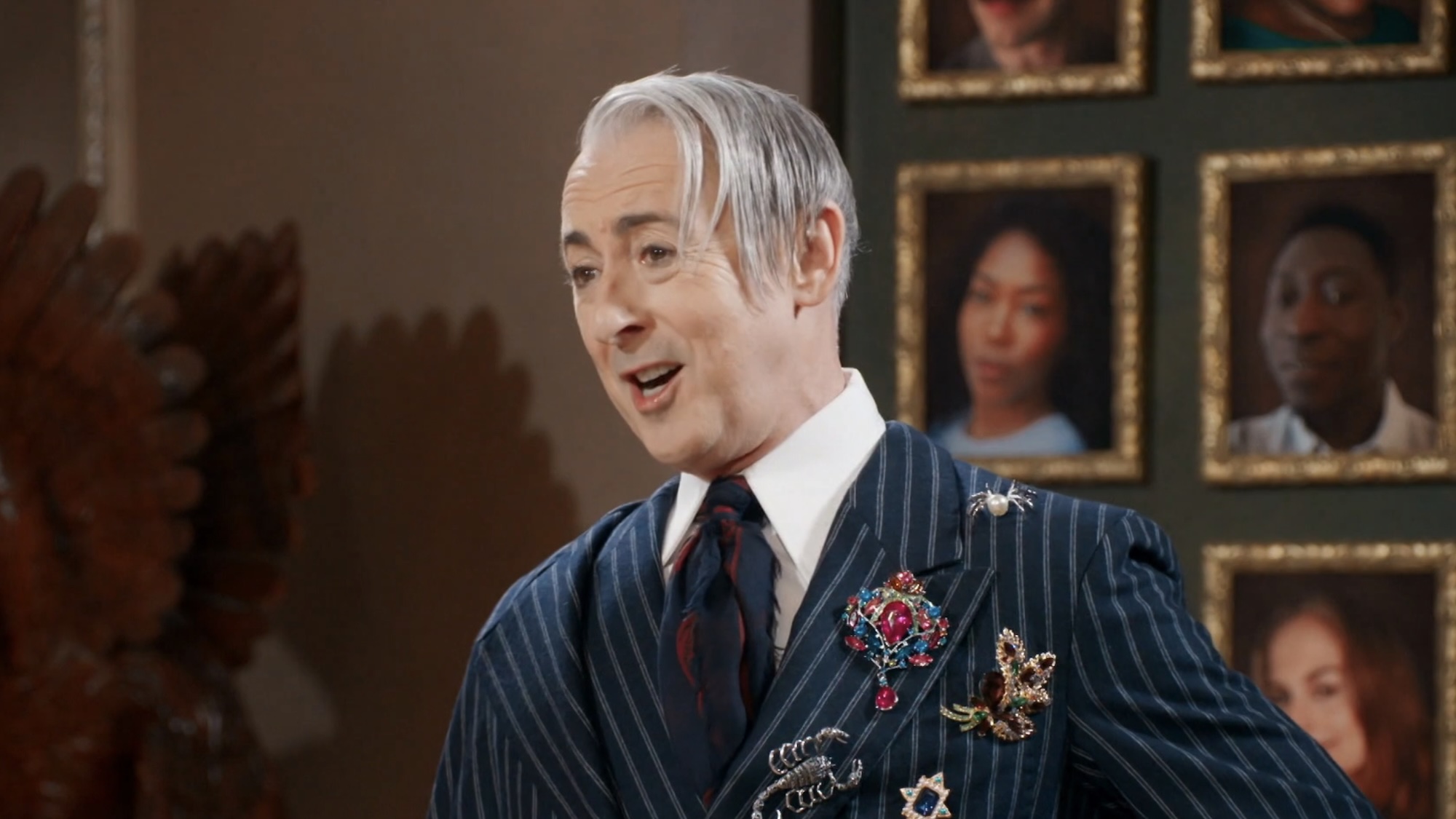 Alan Cumming wearing a blazer and broaches talking to the Traitors: New Blood cast after the first murder. 