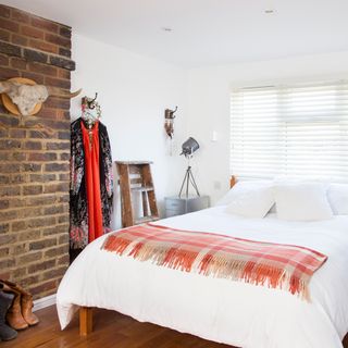 bedroom with white and brick wall wooden flooring white bed and white window