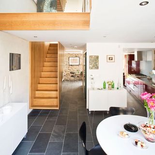 open plan kitchen and dining area with stairwell white wall and slate flooring