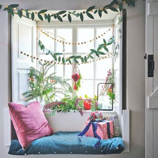 window seat with pink cushion and festive greenery and garlands
