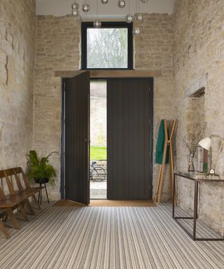 A hallway carpet idea with rustic stone walls, barn door and striped neutral carpet
