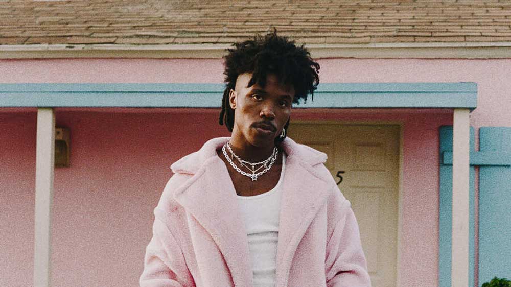 De'Wayne in a pink fur coat outside a pink house