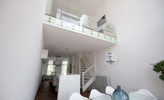 Dining area featuring white walls white walls and decor with wood flooring. Above the dining area is a balcony view from the floor above