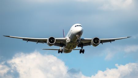 White passenger jet flying in blue sky and clouds