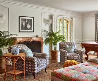 living room with cream paneled walls, fireplace patterned armchairs and ottoman