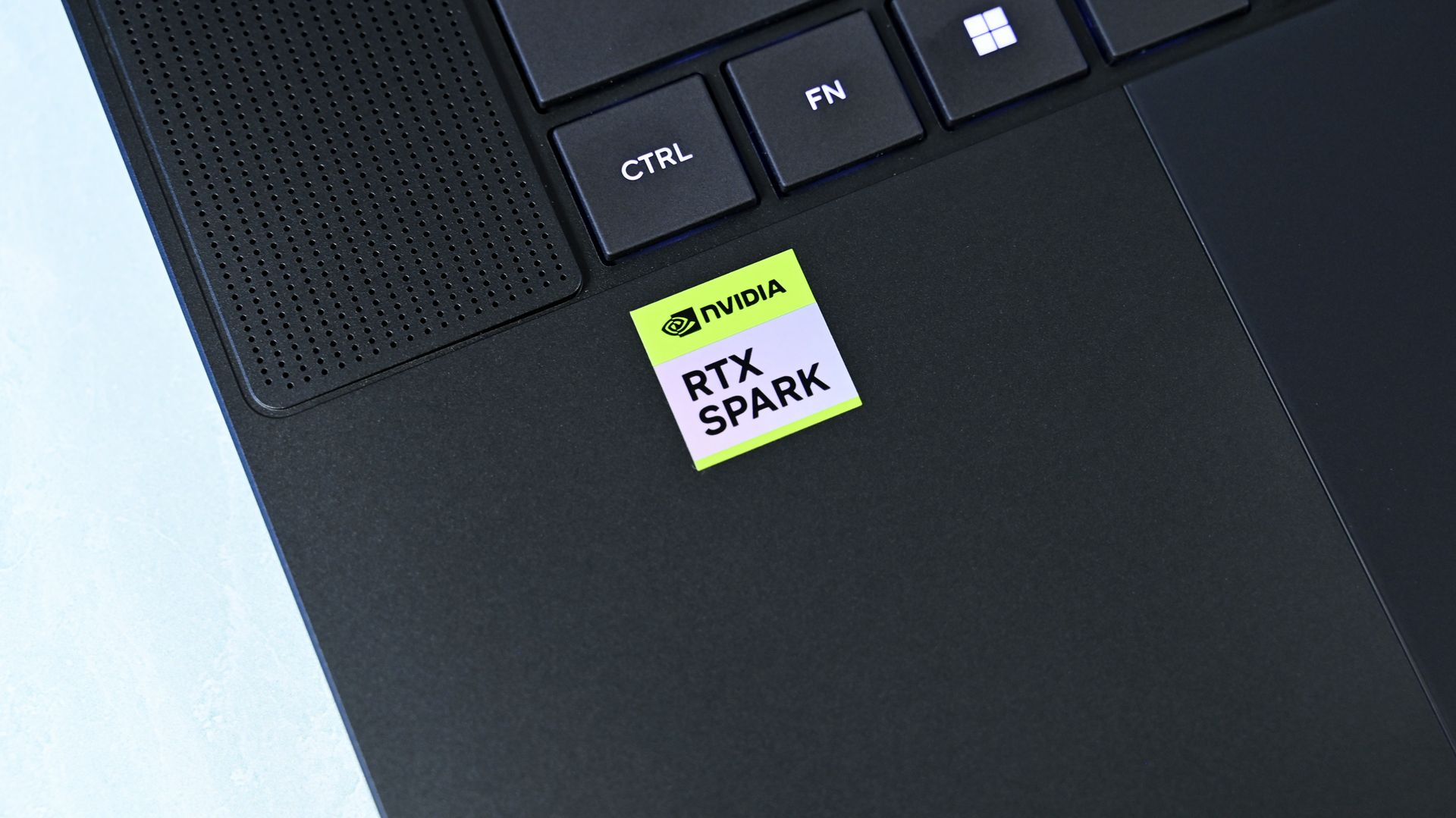 Close-up of the left palm rest on the ASUS ProArt P16 laptop showing the green and white NVIDIA RTX SPARK badge next to the trackpad.