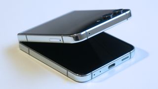 En halvt öppnad Samsung Galaxy Z Flip 5 ligger på ett vitt bord.