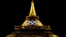 The Eiffel Tower at night, lit up and bearing the Olympics logo.