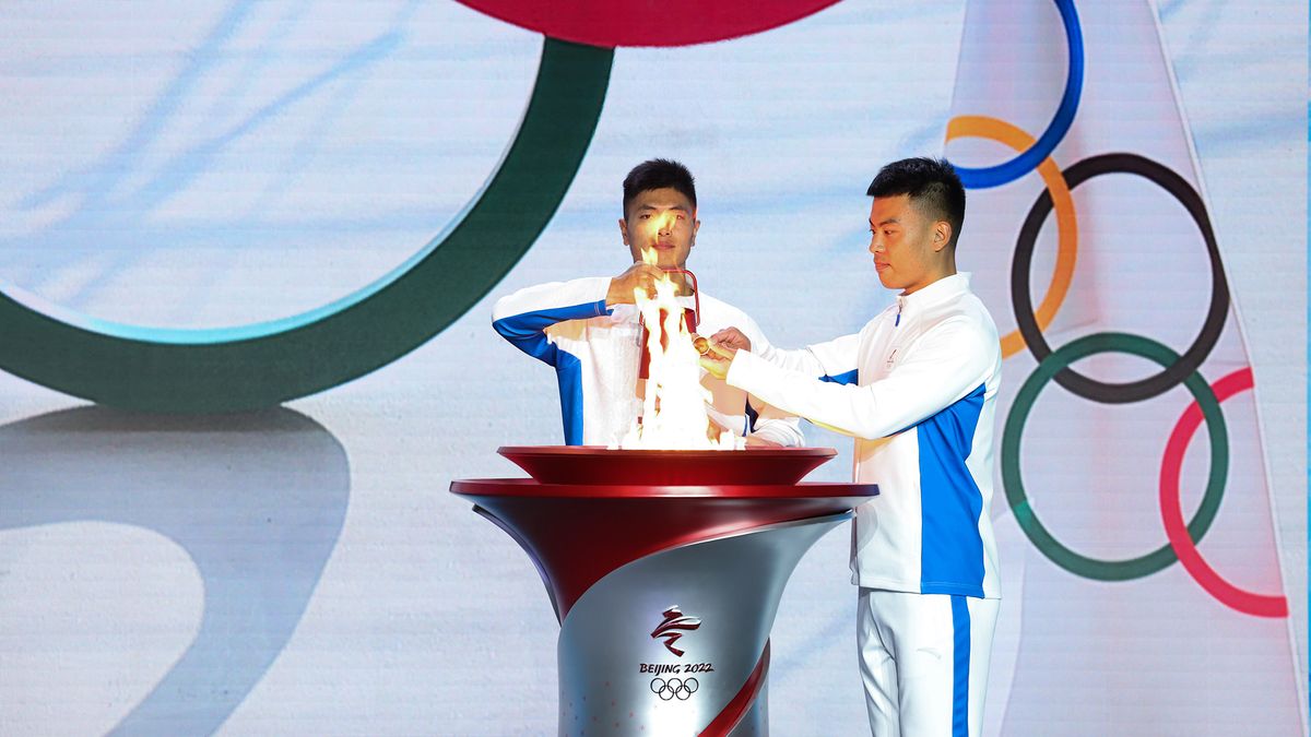 Torchbearers transfer the Olympic flame from a lantern to a torch during the Welcome Ceremony for the Flame of Olympic Winter Games Beijing 2022