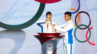 Torchbearers transfer the Olympic flame from a lantern to a torch during the Welcome Ceremony for the Flame of Olympic Winter Games Beijing 2022