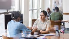 A female military member sits with a financial adviser at a desk.