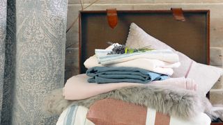 A pile of bedding and blankets in a trunk to show things you should never store in a shed over winter