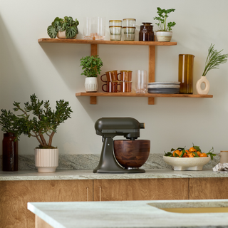 Green KitchenAid mixer on worktop next to fruit bowl