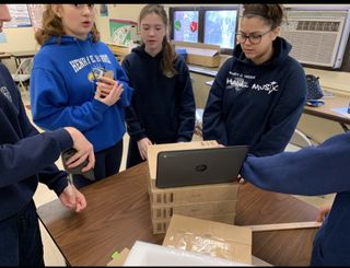 A group of students standing around a computer.