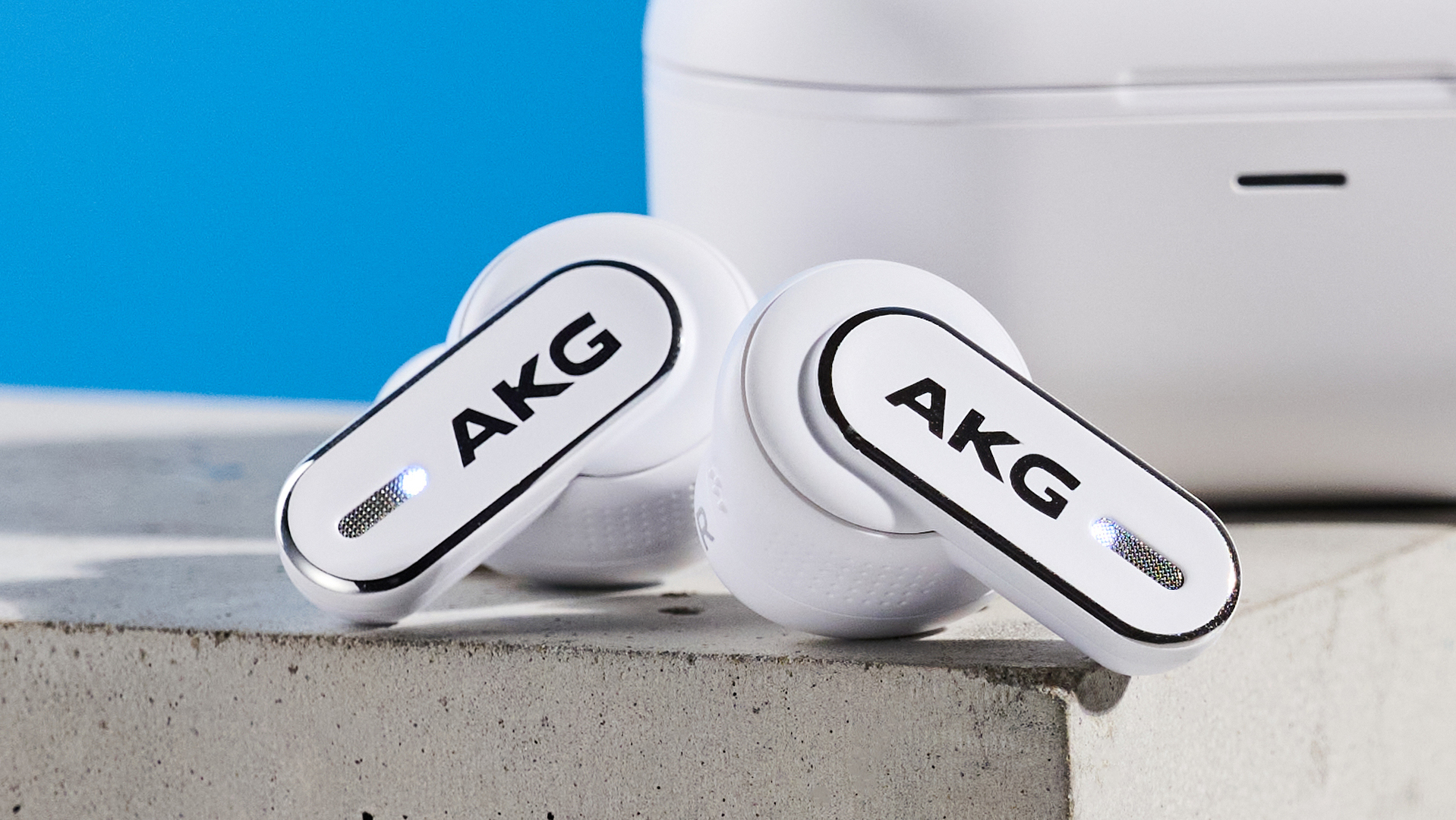 the akg n5 hybrid earbuds by harman in white, shown in their charging case with accessories and without