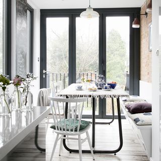 A white dining room with black french doors and a wooden table and chairs
