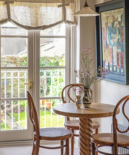 a small breakfast nook in the corner of a kitchen with a wooden twisted table and vintage chairs