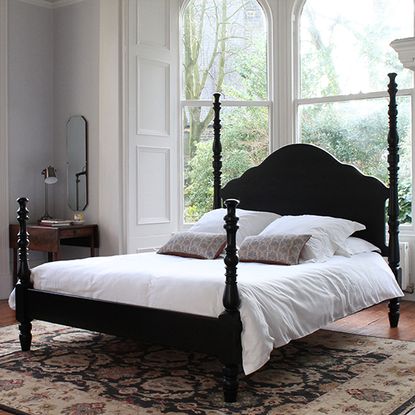 Ebony Kingston bed with white bedlinen on carpet in bedroom by window