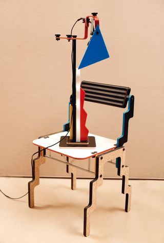 An abstract lamp sits on a cut out wooden chair