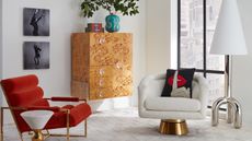 Corner of a living space with plush white and red cocktail chairs, a burled wood bar cabinet and chrome floor lamp