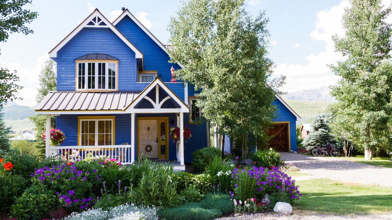 A beautiful flower garden in the front yard of a blue house