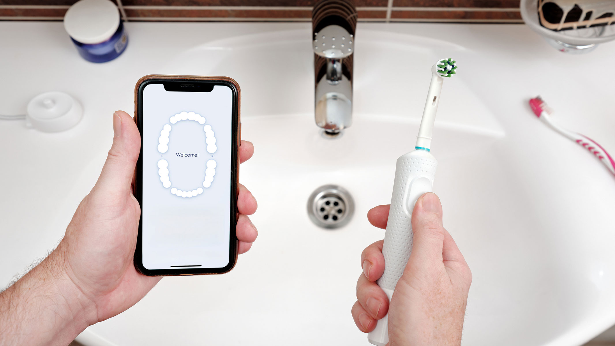 A close-up picture of a man holding a phone and an electric toothbrush