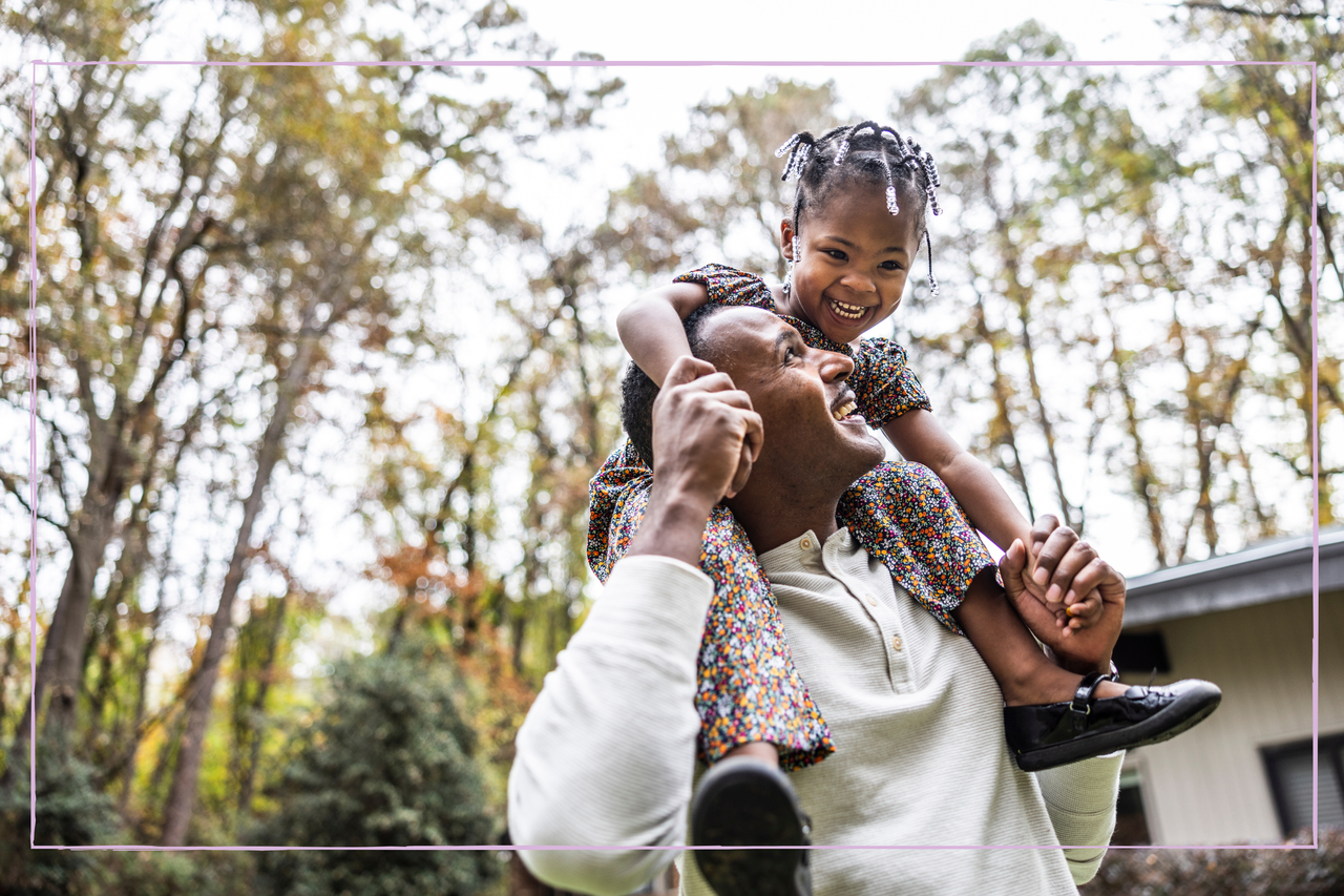 Positive and happy father carrying his daughter on his shoulders