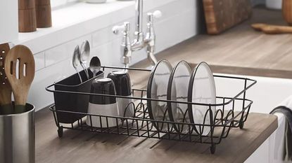 simplywire Black Dish Drainer with Cutlery Basket, one of the best dish drainer options, in a white and wooden kitchen next to a sink