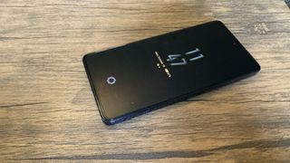 A Cyber Black Infinix GT 10 Pro camera phone on a brown wooden table