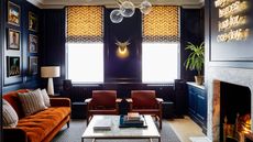 Living room with dark blue wood paneled walls, fireplace with marble surround and neon light on the chimney breast, a David Bowie lyric We can be Heroes Just For One Day. A restored Georgian Grade II listed townhouse converted from an office building in London.