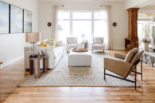 Bright and airy living room with wooden floors large windows and white and tan furnishings