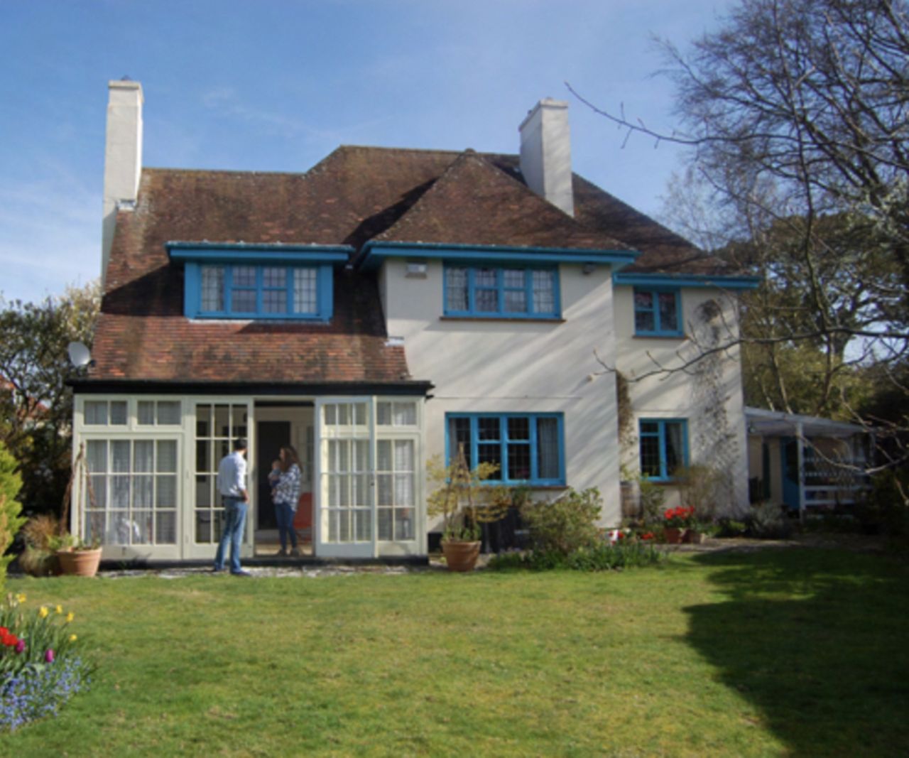 The before shot of a detached home with blue window frames and drainpipes before a new extension is added