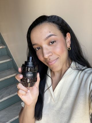 Lauren Tappan holding a bottle of Viktor & Rolf Spicebomb in front of steps.