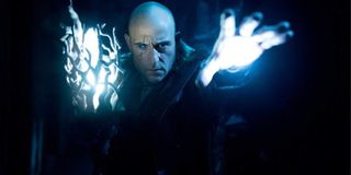 Shazam! Mark Strong stands menacingly in the cave with his glowing hand and staff