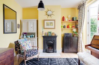 A small yellow living room with alcoves, black fireplace and patterned navy blue Berber rug