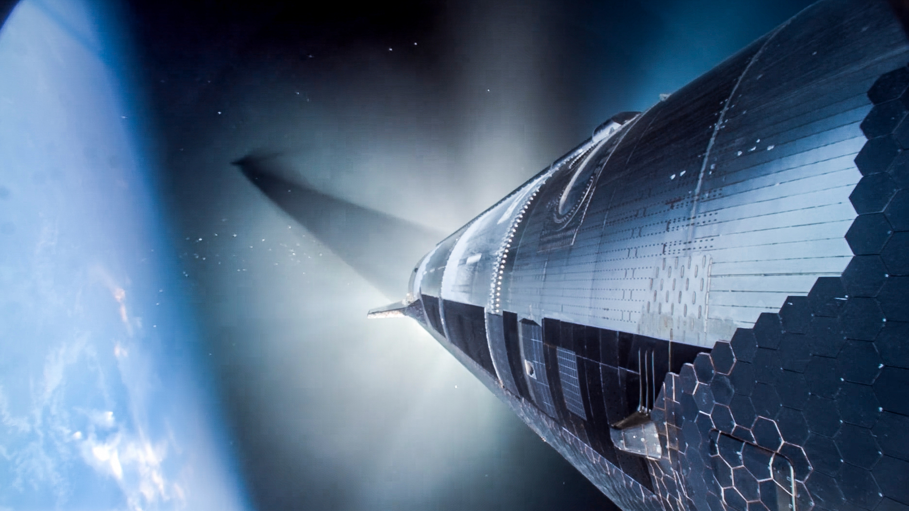 a large, cylindrical, silver metallic spaceship flies in earth orbit