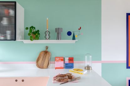 A kitchen with green and pink paint tones on walls