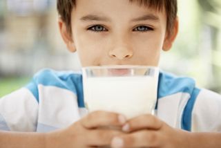 a boy drinking a big glass of milk