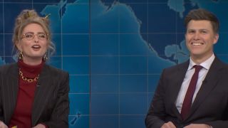 Sarah Sherman laughs while dressed as an accountant, and Colin Jost smiles as she roasts him on Weekend Update.