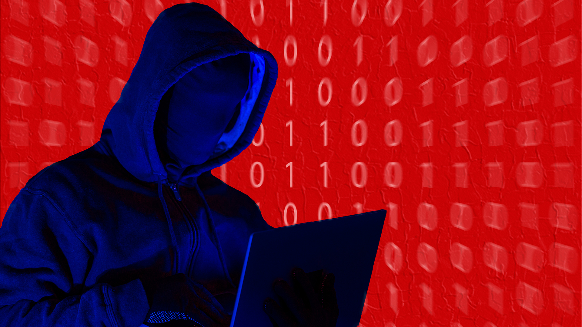 Hacker concept image showing silhouette of a hooded individual using a laptop computer with binary code imposed against a red backdrop. 
