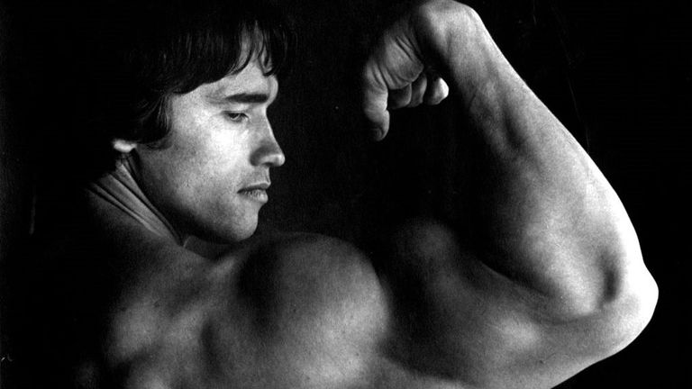 Arnold Schwarzenegger flexing his enormous biceps