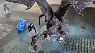 A dragon miniature faces off with hero characters on the board of Dungeons & Dragons: Onslaught
