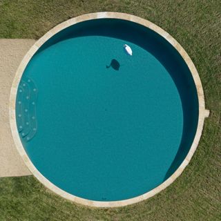An aerial view of the round swimming pool surrounded by a green lawn.