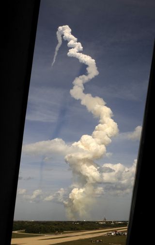 Atlantis soars skyward as seen through the louvered windows of the Launch Control Center at Kennedy Space Center in Cape Canaveral, Fla.