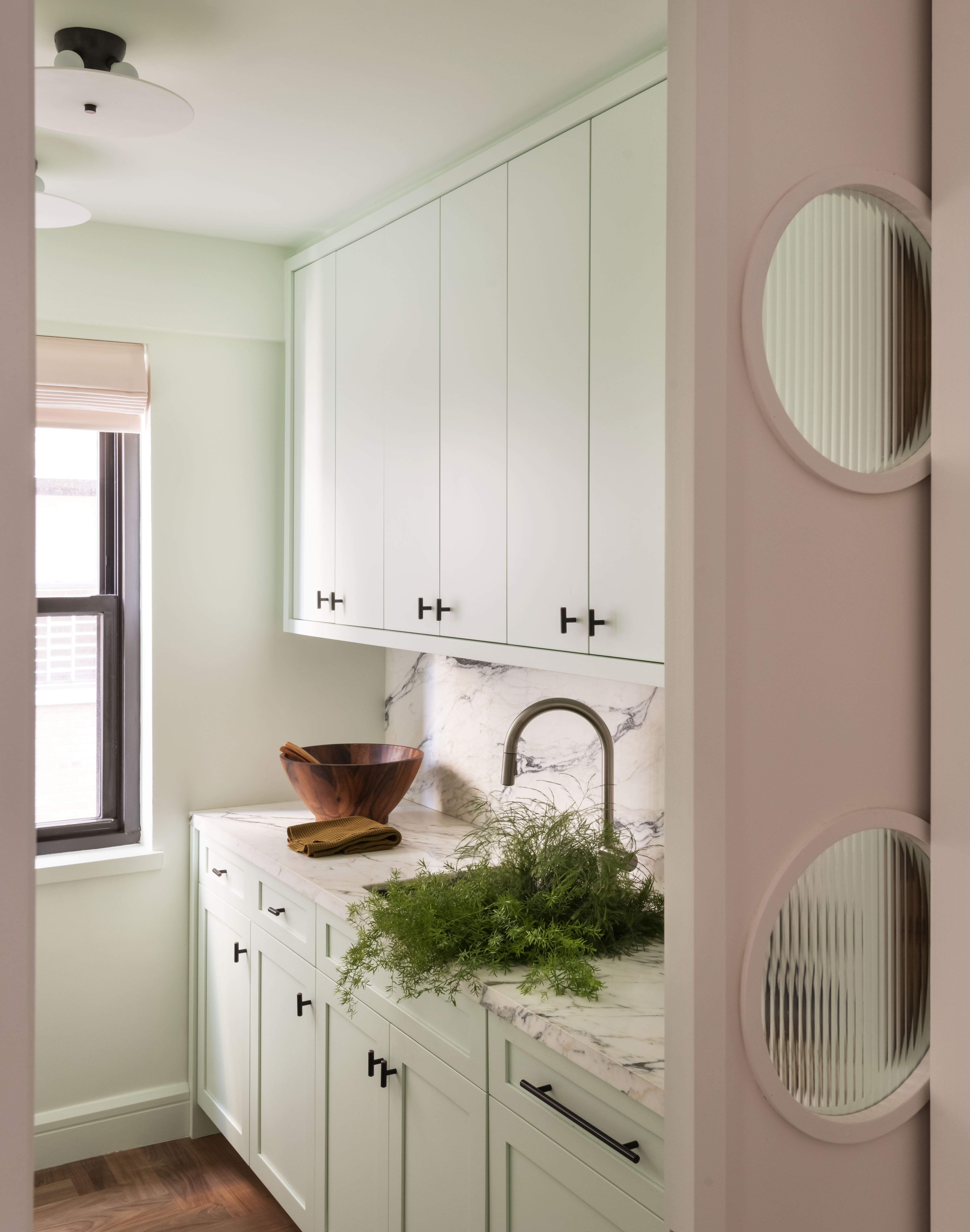 A small kitchen hidden behind a sliding door, filled with pastel hues