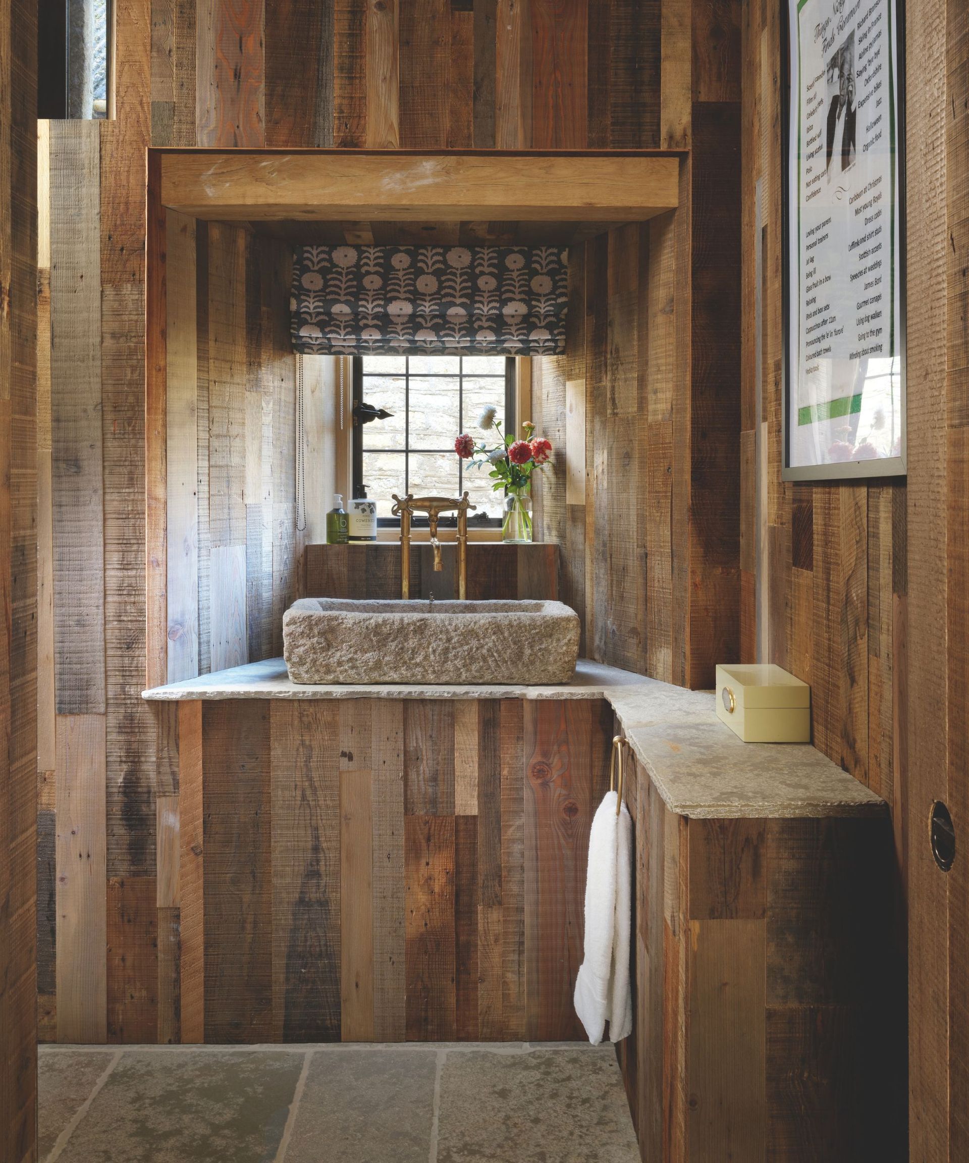 bathroom with wood paneling on all wall surfaces and textured rough stone sink